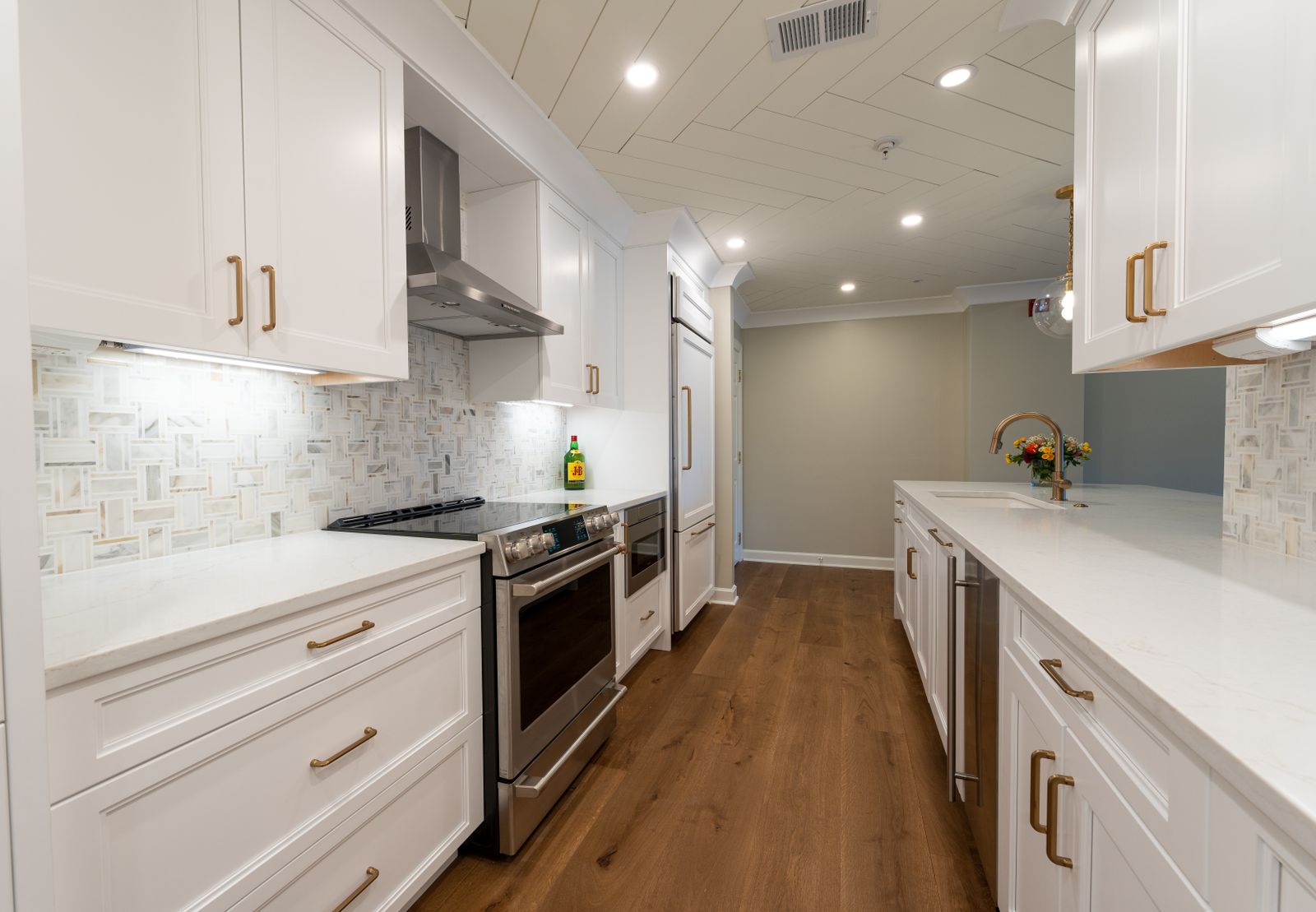 Dark wood-effect plank flooring running through a white kitchen